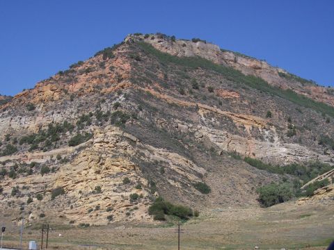 1972 Ford Ranchero - A vast mountain landscape with distinct geological layers and sparse vegetation under a bright blue sky.