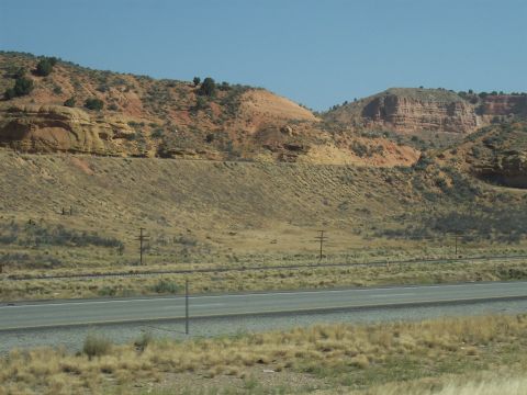 1972 Ford Ranchero - A wide view of a desert landscape rolling hills, red rock formations, and a highway stretching into the distance.