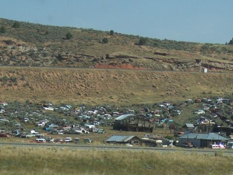 1972 Ford Ranchero - A vast junkyard filled with many vehicles, set against a backdrop of a dry, hilly landscape.