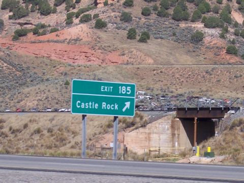 1972 Ford Ranchero - A highway sign indicates exit 185 for Castle Rock, with a view of parked vehicles beyond a bridge.