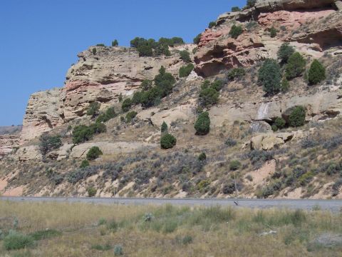 1972 Ford Ranchero - A dry, rocky hillside with sparse vegetation and a road is visible under a clear blue sky.