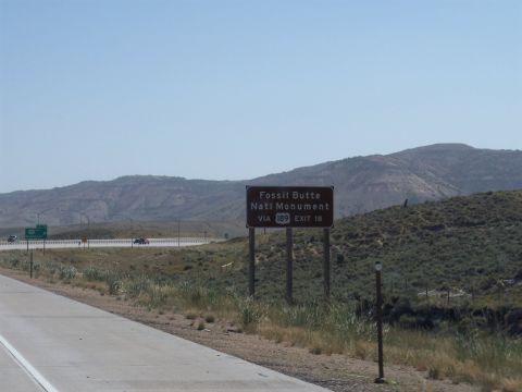 1972 Ford Ranchero - A sign directs travelers to Fossil Butte National Monument from the highway, with arid hills in the background.