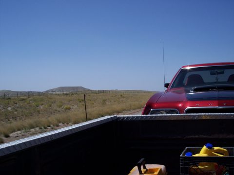 1972 Ford Ranchero - Red car with black hood scoop parked on a roadside with a rural landscape.