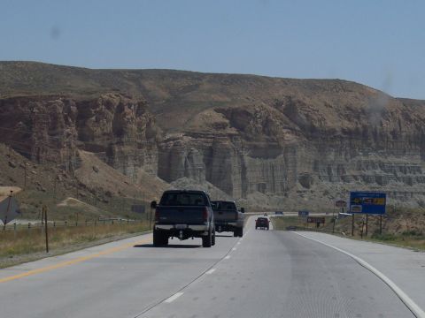 1972 Ford Ranchero - Several trucks drive along a highway with a dramatic canyon backdrop under a clear blue sky.