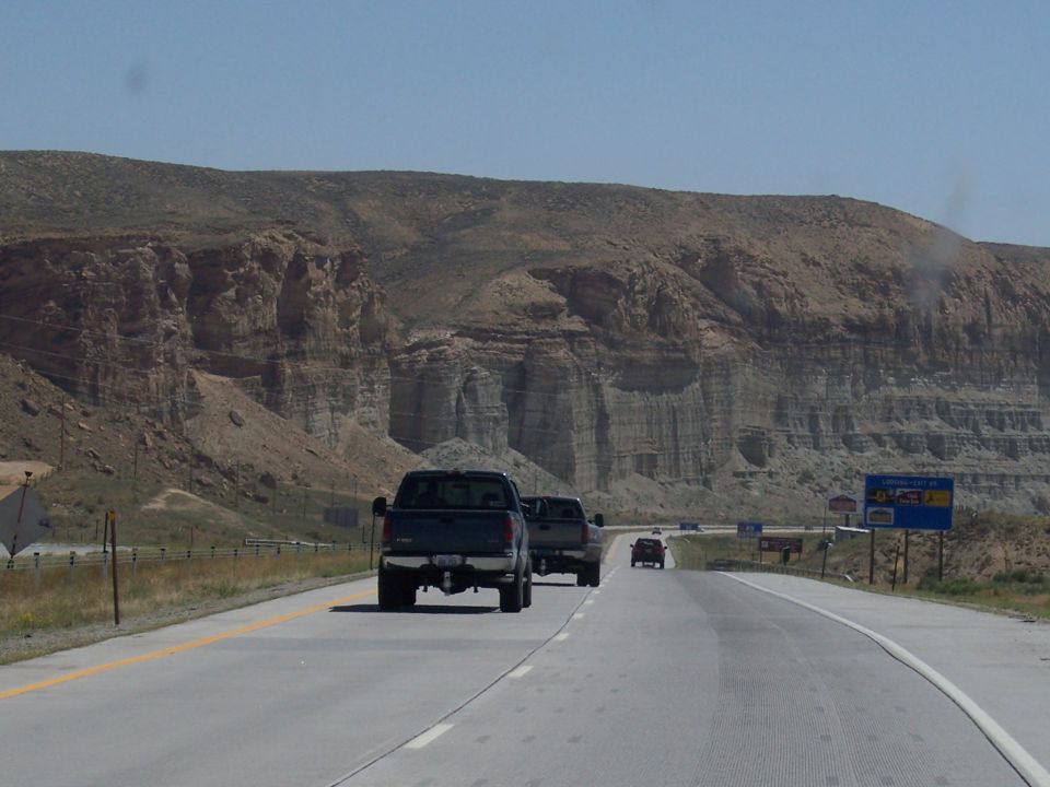 Dark pickup trucks on a highway with a rocky mountain landscape