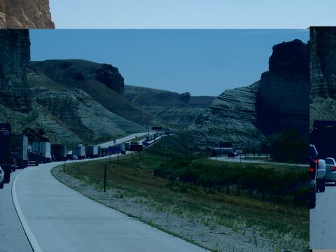 1972 Ford Ranchero - A long line of vehicles is stopped on a highway that winds through a rocky canyon landscape.