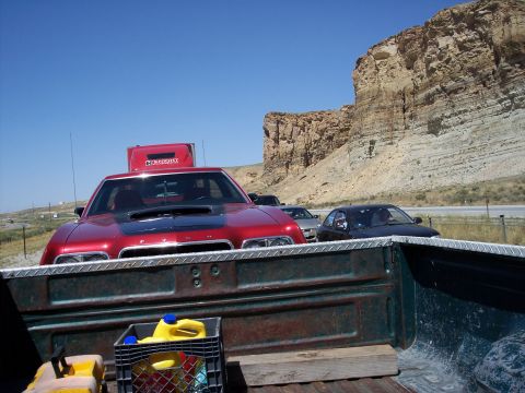 1972 Ford Ranchero - Red car and semi-truck cab seen on a road trip with rocky cliffs in the background.