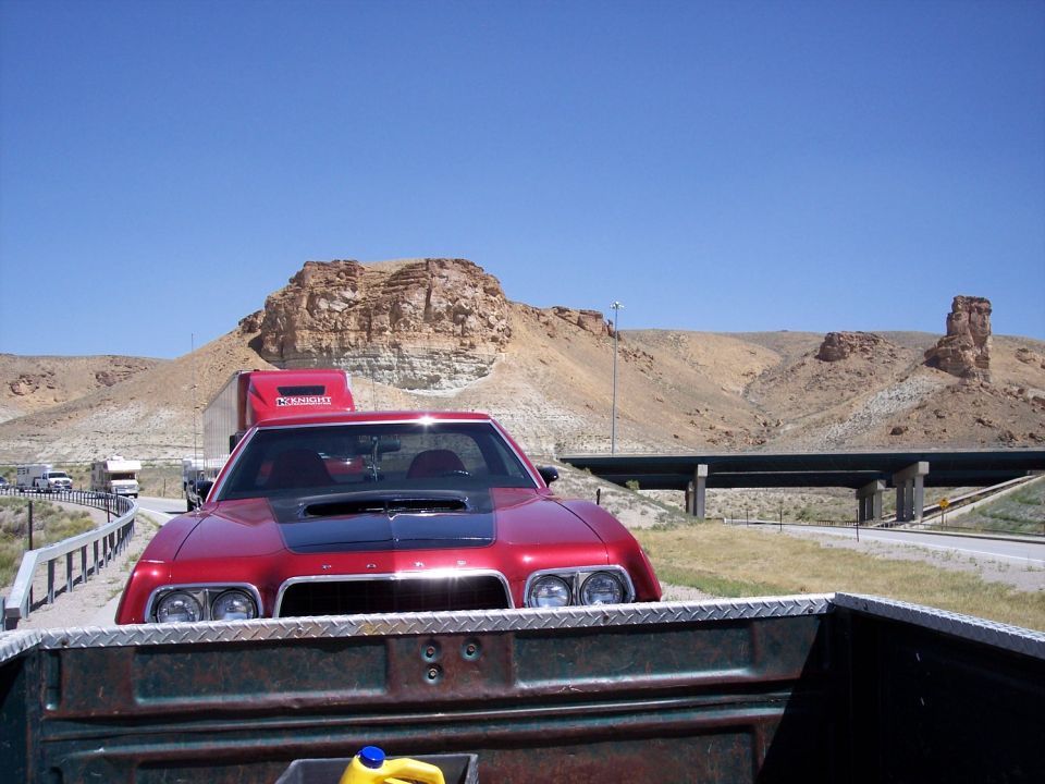 Red 1972 Ford Ranchero with black hood scoop, front view, parked on roadside