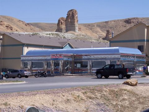 1972 Ford Ranchero - A black pickup truck drives by a classic diner with unique rock formations in the distance.