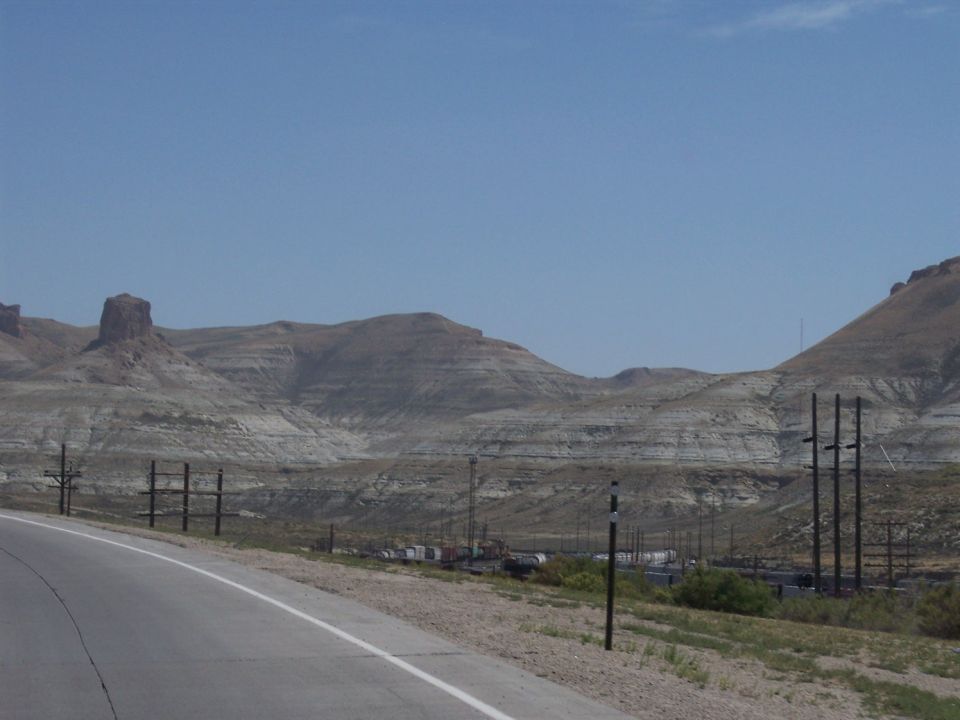 Desert landscape with layered hills and a road curving to the left