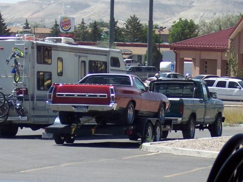 1972 Ford Ranchero - A red 1972 Ford Ranchero is transported on a trailer, towed by a green pickup truck, with a Burger King sign in the background.