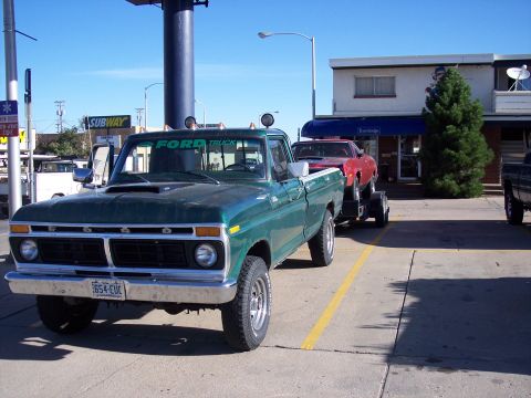 1972 Ford Ranchero - Green 1975 Ford F-Series pickup truck is towing a red car on a trailer.