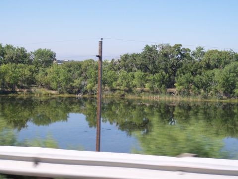 1972 Ford Ranchero - A calm body of water reflects the lush green trees and clear blue sky on a sunny day.