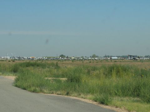1972 Ford Ranchero - A vast expanse of vehicles sits in a field, with an oil pump visible in the distance.
