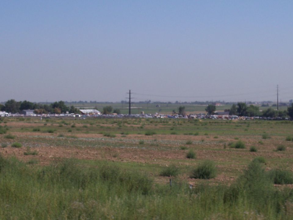 Distant view of multiple vehicles parked near buildings under a hazy sky