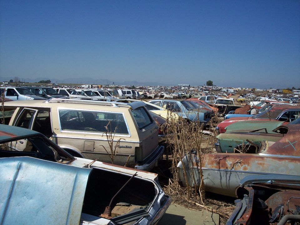 Junkyard scene with many old cars under a clear blue sky