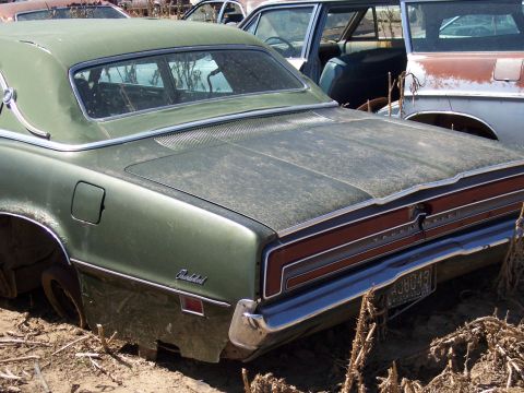 1972 Ford Ranchero - Rear view of a green 1970 Ford Thunderbird in a junkyard, showing its distinctive taillights and script emblem.