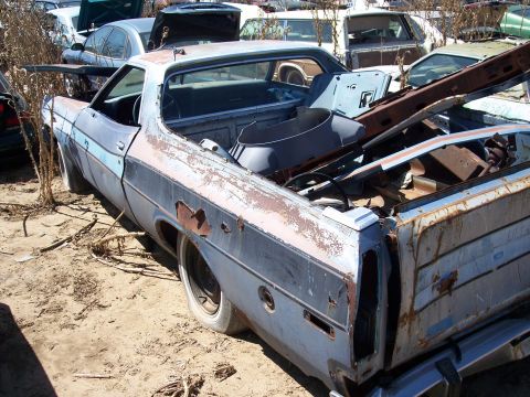 1972 Ford Ranchero - A 1972 Ford Ranchero sits in a junkyard, showing significant rust and damage.