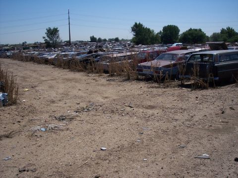 1972 Ford Ranchero - A vast junkyard filled with numerous vehicles under a clear blue sky.