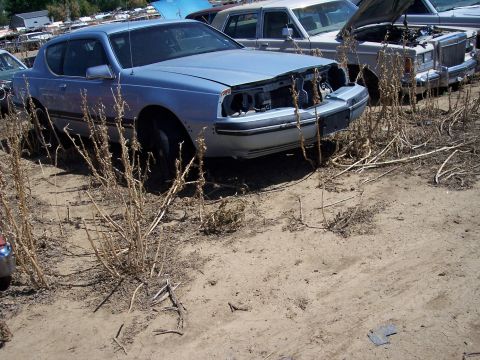 1972 Ford Ranchero - A light blue coupe sits in a junkyard, its front end dismantled.