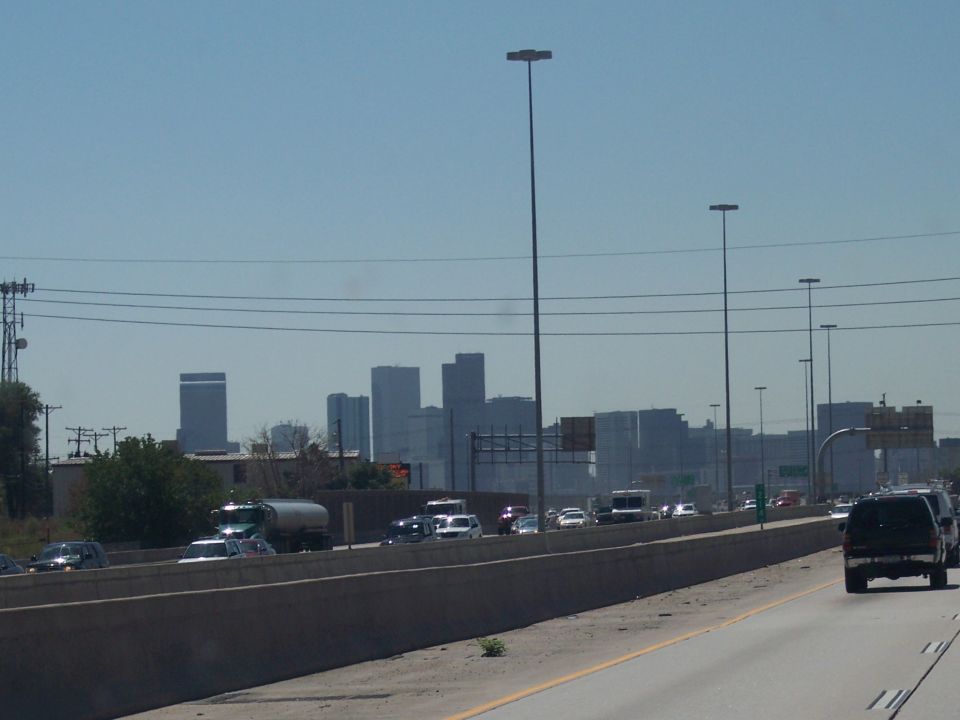 Highway traffic with a city skyline in the background under a clear blue sky
