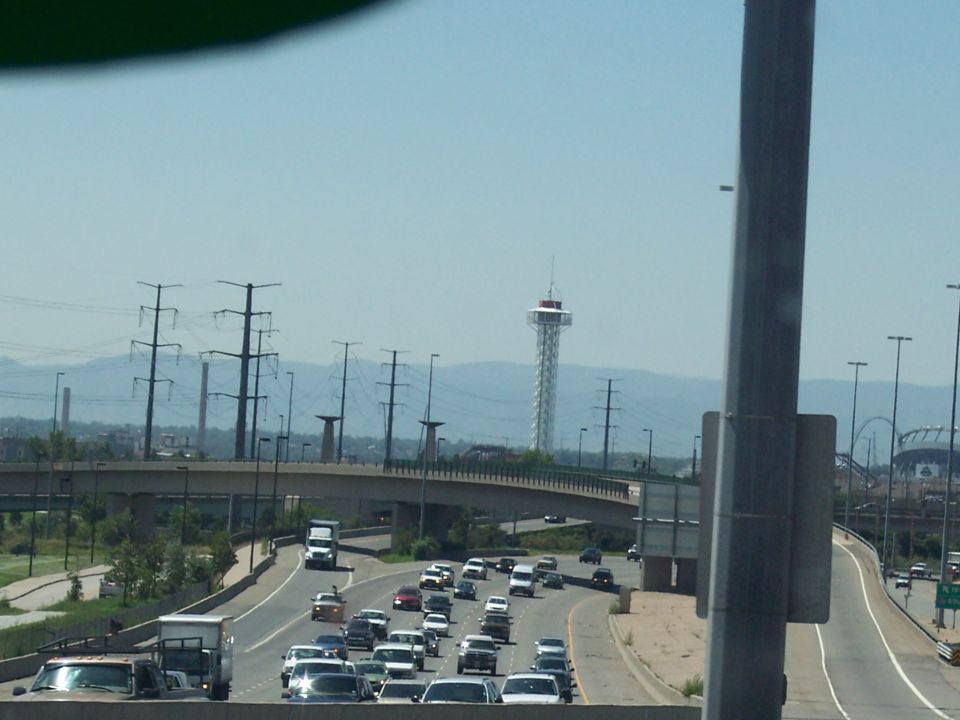 Traffic on a highway with a tall tower and mountains in the background