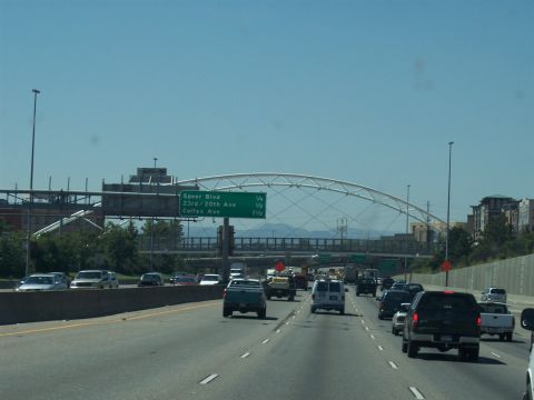 1972 Ford Ranchero - Vehicles travel on a multi-lane highway under a distinctive arch bridge, with city buildings visible on the horizon.