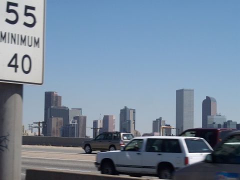 1972 Ford Ranchero - Vehicles travel on a highway with a clear blue sky and a distant city skyline.