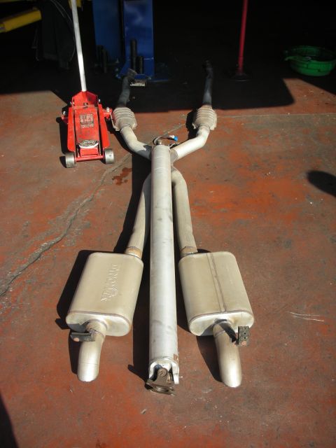 1992 Ford Crown Victoria - Exhaust system removed from a vehicle, possibly for replacement or repair. A hydraulic jack is visible nearby.