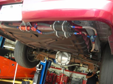1992 Ford Crown Victoria - Custom fuel system components are visible under the red vehicle, which is on a lift in a garage.