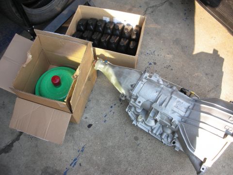 1992 Ford Crown Victoria - A transmission and torque converter are laid out on a concrete surface next to boxes of motor oil.