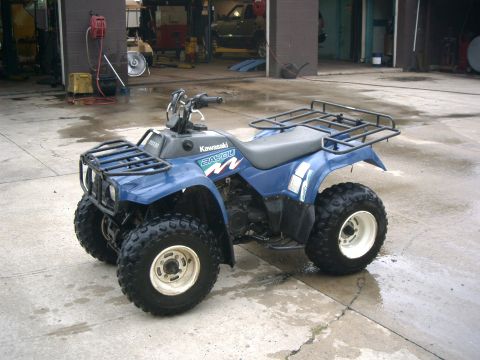 1991 Chevrolet Suburban - A blue Kawasaki Bayou ATV is parked on a wet concrete floor inside a garage.