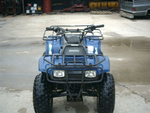 1991 Chevrolet Suburban - A blue ATV is parked outside a garage with equipment in the background.