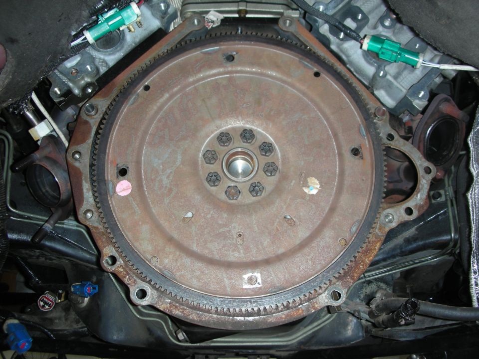 Close-up of a rusty engine flywheel with bolts and a gear ring