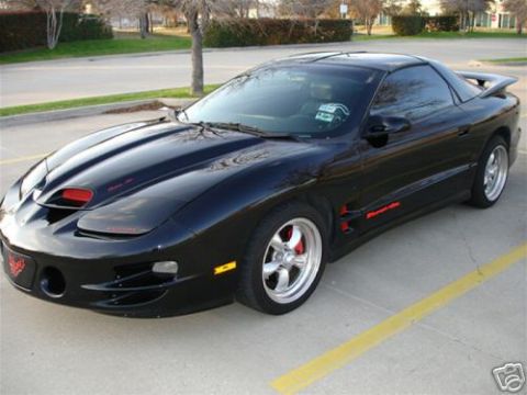 2002 Pontiac Trans Am - A black 2002 Pontiac Trans Am is parked in a lot, showing its distinctive hood scoops and side badging.