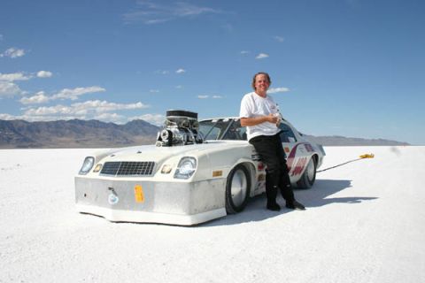1987 Ford Thunderbird - A man poses with a heavily modified drag car on a bright, sunny day at a salt flat location.