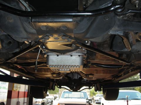 1992 Ford Crown Victoria - Underside view of a vehicle's transmission and suspension system, with other vehicles in the background.