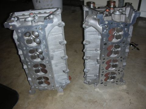 1998 Ford Crown Victoria - Two engine cylinder heads are shown on a concrete floor, likely for sale or repair.