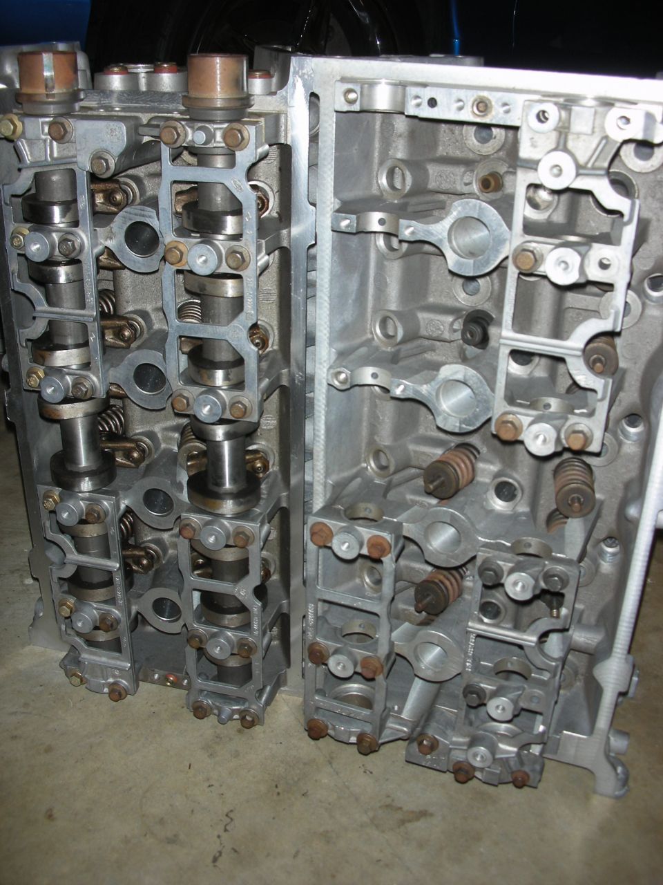 Two aluminum engine cylinder heads with camshafts and valve springs visible