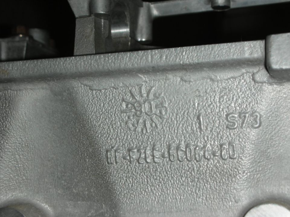 Gray metal engine part with casting marks and part number F2TE-6060-BO