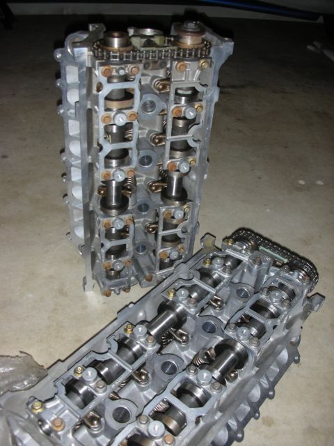 1998 Ford Crown Victoria - Two engine cylinder heads are shown, revealing their internal camshaft and timing chain mechanisms.