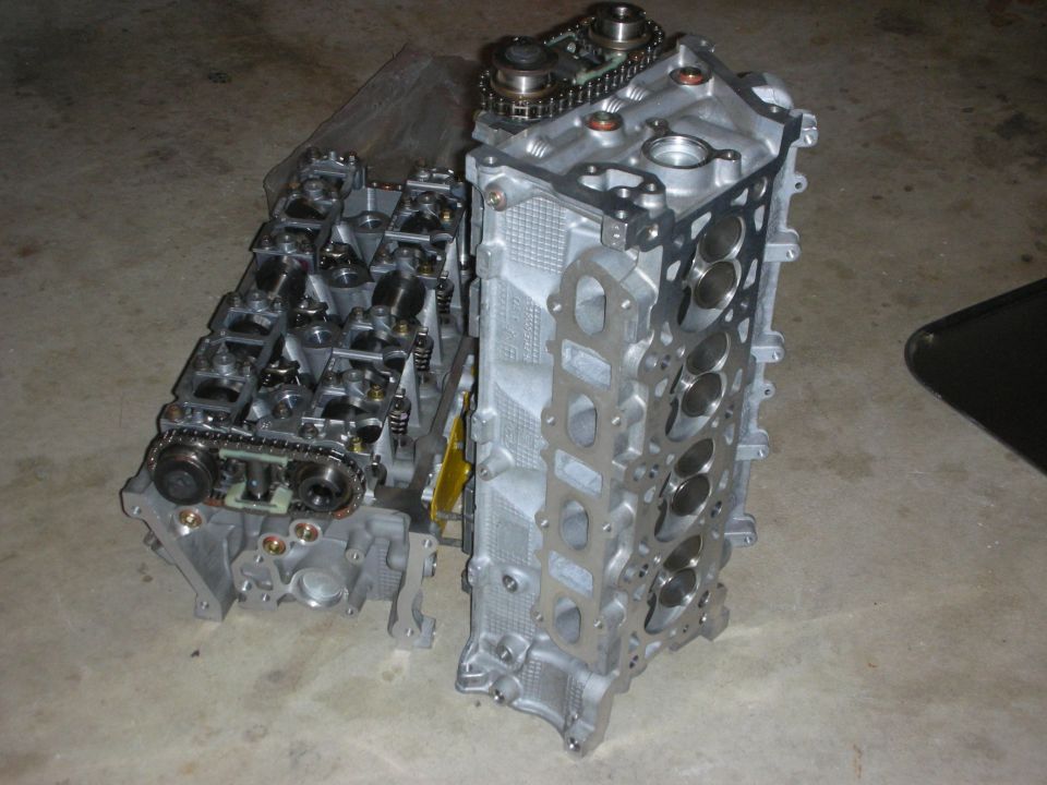 Two engine cylinder heads, one with timing chain and sprockets
