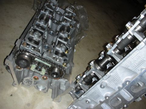1998 Ford Crown Victoria - Engine cylinder heads with camshafts and timing chain components are laid out on a floor.