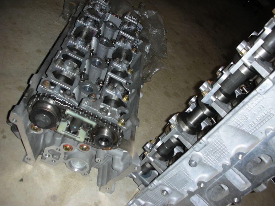 Two engine cylinder heads with camshafts and timing chain visible