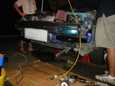 1995 Mazda MX-6 - The front of a car is taken apart, revealing the engine bay and a large intercooler installation.