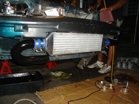 1995 Mazda MX-6 - Intercooler and piping installation underway on a teal vehicle, supported by jack stands.