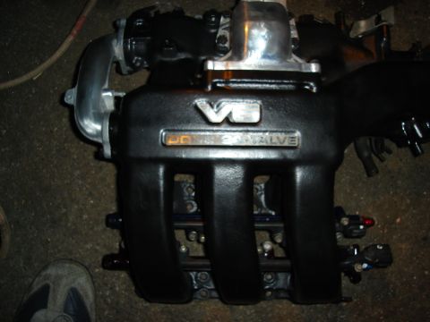 1995 Mazda MX-6 - Close-up of a V6 engine intake manifold, 'DOUBLE OVERHEAD VALVE' badging and custom black paint.