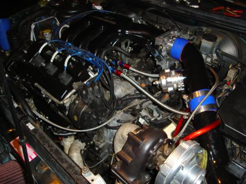 1995 Mazda MX-6 - Engine bay modifications include a turbocharger and custom intake piping, obscuring original vehicle details.