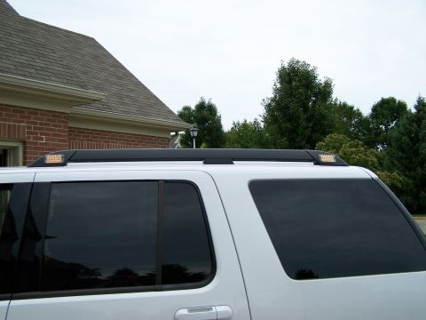 2003 Ford Crown Victoria - White SUV with aftermarket roof rack lights installed.