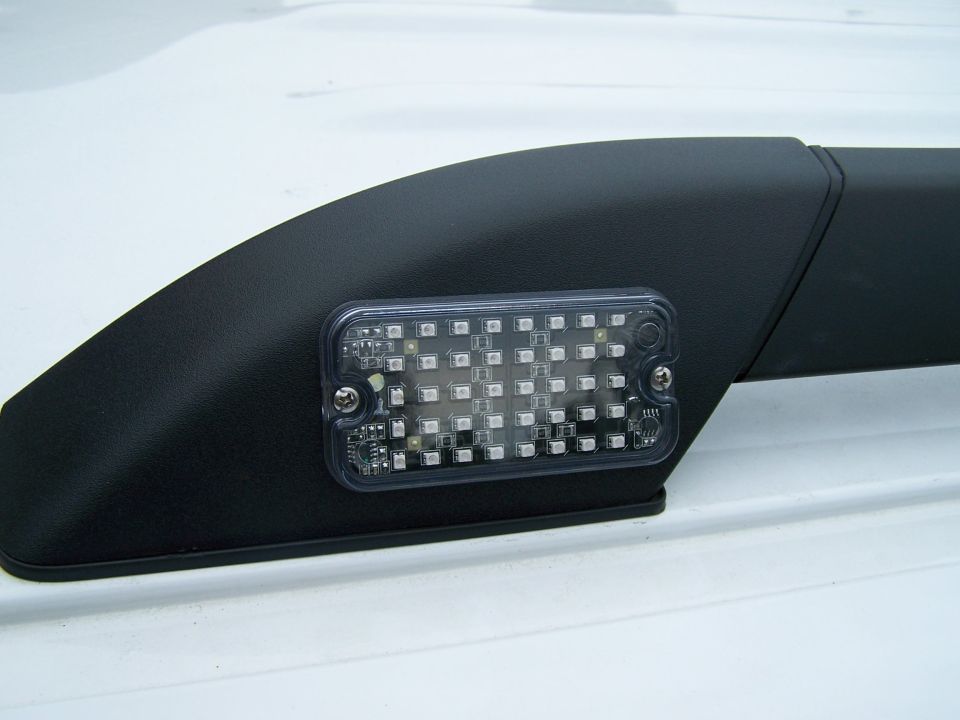 Close-up of an aftermarket LED light bar mounted on a black roof rack rail